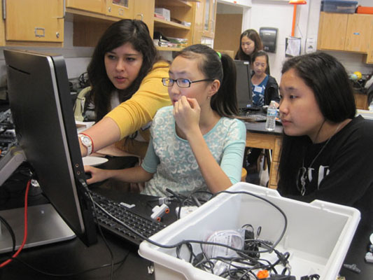A.W.E.S.O.M.E. Almeida: Assisting middle schoolers, senior Gabriela Almeida explains how to change program commands to make the robot move successfully. Almedia enjoyed watching the girls develop their engineering interests and succeed with her help. 