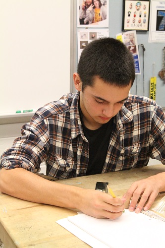 Using various tools, a male student designs his next project in jewelry class.