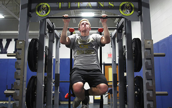 BUILDING STRENGTH: In gearing up for their spring season, junior Jake Smiley utilizes a new pull-up bar to improve his strength for baseball.