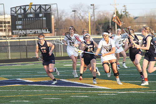 EYES ON THE PRIZE: Running past Oak Park River Forest defenders, Lindsey Karsh, junior midfield and attack (left) tries to keep cradling the ball while moving down the field during a game on April 14. The Titans beat Oak Park River Forest BY a score of 16-6. 
