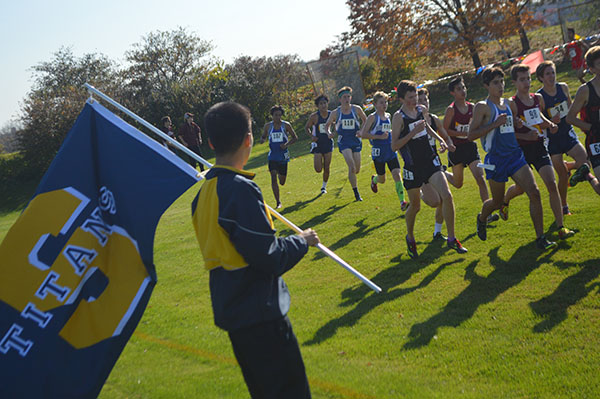 starting   sophomore:  Waving a flag, junior Daniel Cho supports his team while at the IHSA Regionals meet, which was held at Loyola Academy, where the Titans placed second out of ten teams (left). This was the last meet before Sectionals where they placed eighth to finish their season.  