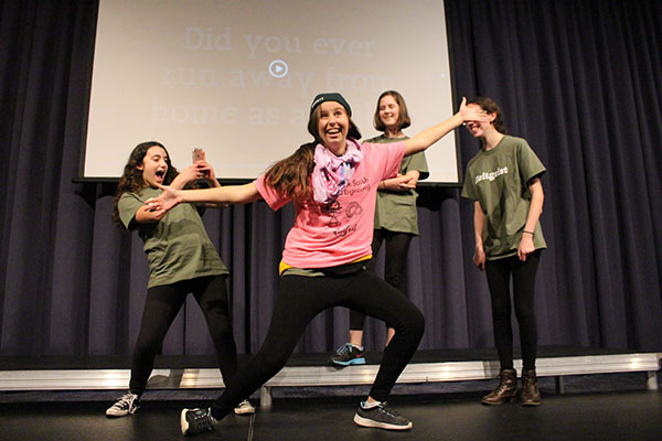 Zealous for Zeitgeist:  Acting out a scene in Zeitgeist, sophomores Sammi Boas and Sarah McNeela laugh as Gabriella Bellows photographs sophomore Annabelle Fogel. The theme of the play, growing up, was chosen by the cast of freshman and sophomore students. In addition, the actors wrote the entire script of the play.