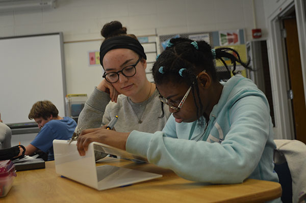 A Helping Hand: Engaged in classwork, a mentor and student work to complete a writing worksheet. Mentors use their elective time to work with the students in the classroom to create a comfortable setting for all involved in the program. 
