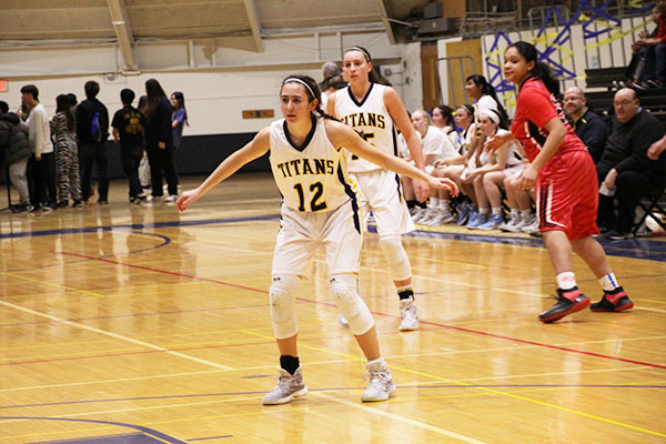 HANDS OUT :  Facing a Niles West offender, junior Lizzie Shaw prepares to stop a drive to the net during a game on Feb. 3. The Titans currently hold a 20-4 record.