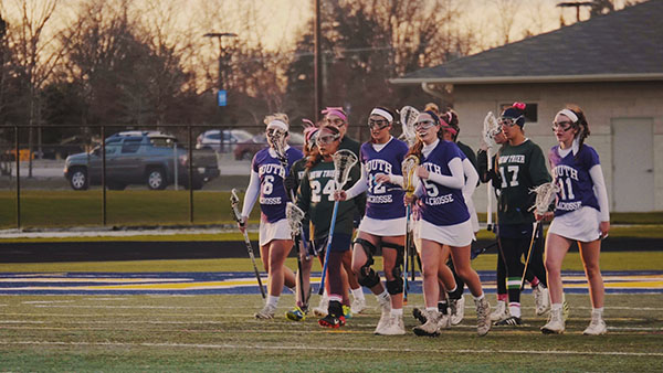 The rest of the players on the field (right) walk back to the draw circle after scoring against the Trevians. The women lost to New Trier by a score of 14-7, according to captain Sophie Hensley.