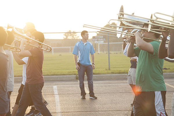 BEAMING BORON:  Standing between a line of trombones, co-band director Brian Boron watches intently as the GBS marching band rehearses. Boron, a Glenbrook North graduate, was part of the GBS band staff last year as a percussion instructor and started his first year as co-band director this fall. 