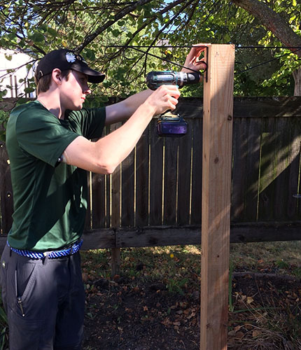 EAGER TO ACHIEVE EAGLE: Assembling a bird-feeder post, Life Scout Colb Uhlemann uses a drill to hang metal hooks in order to put up the bird feeder. Uhlemann makes the bird feeder post in The Grove for his Eagle Project, hoping to achieve Eagle Scout status for community service work. Photo courtesy of Will Dunk