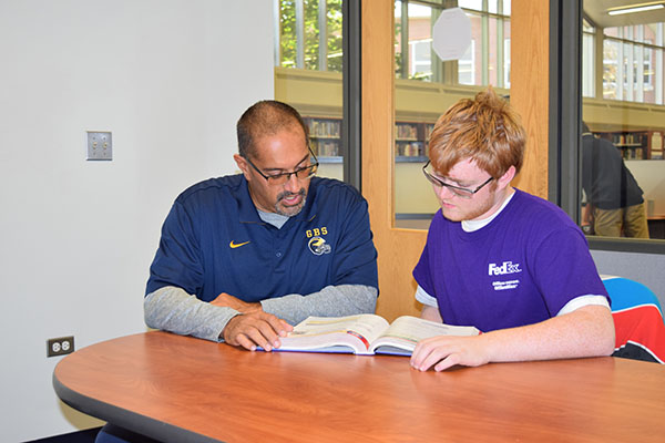 PASSIONATE PROFESSOR: Reading a textbook, Pa’al Joshi, special education teacher, helps one of his students with math. Joshi receives Symetra Heroes in the Classroom Award for his contributions to South’s special education program.