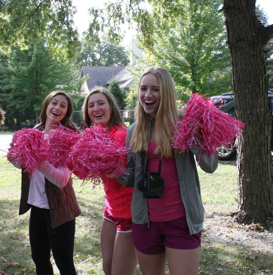 STRIDES FOR A CURE:   Cheering at a Cure Club event (left), sophomores Lina Pedrelli, Sammy Tvaroh and Erin Nukk smile for the camera. Gathering for a group photo (right),  Cure Club members huddle together after their Stride for a Cure event. Last year, Cure Club raised approximately $50,000 for cancer research, a number they hope to surpass this year.