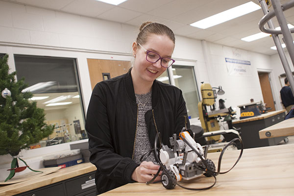 KATE THE GREAT:   Smiling as she works, sophomore Kate Stack spends time after school in the MakerSpace to improve a robot. This year, Stack was awarded a $10,000 grant from Infosys, which she gave to the Glenview Public Library to foster engineering interest in the community. 