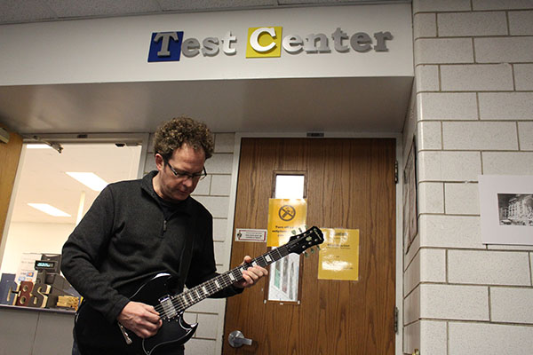 MAKIN’ MUSIC: Jamming out, McInerney strums his guitar outside the test center. McInerney enjoys playing guitar, and hopes to start a guitar club someday here at South. 
Photo by Eliza Schloss