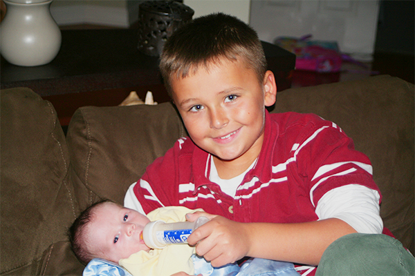 BROTHERLY BOND: Feeding his baby brother, junior Jacob Snyder practices his new big brother duties. Snyder’s family, who adopted their Safe Family child, is just one of many South families who have participated in the Safe Families foster care program, where children from families in crisis get the help they need until things become more stable at home. 