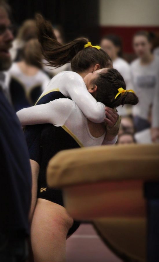 ECSTATIC EMBRACE:  Celebrating their win, sophomore Jenna Hartley and senior Bebe Haramaras hug after finishing a routine. The girls went on to place 3rd at state.