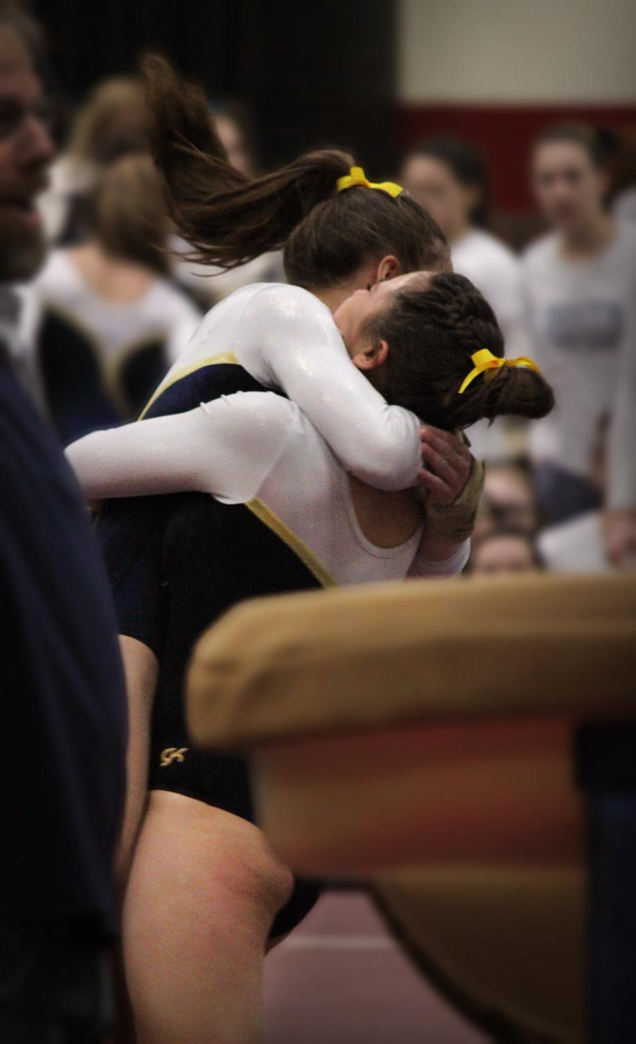 ECSTATIC EMBRACE: Celebrating their win, sophomore Jenna Hartley and senior Bebe Haramaras hug after finishing a routine. The girls went on to place 3rd at state.