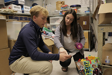 PROUD PRESIDENT:  Labeling a box of donated food, 2017-2018 Student Body President Abby Grant talks things over with junior Matthew Baumstark. Grant oversaw changes to the canned food drive, amongst other revisions made this year. 