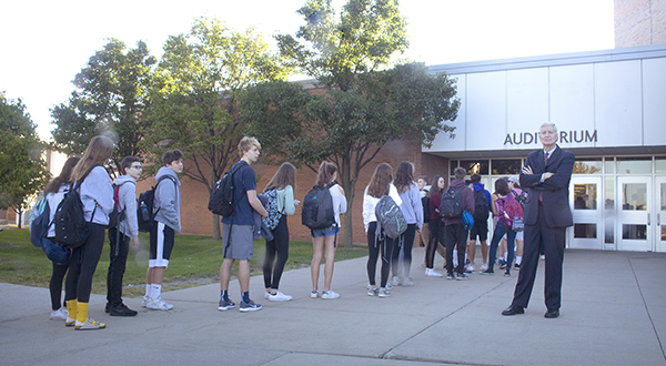 it   can   happen   anywhere: Forming a line outside the auditorium doors, students wait for their belongings to be checked by faculty and administrators before school on Monday. Sept. 24 while Superintendent Dr. Michael Riggle supervises. This security measure was implemented after a message reading “there will be a school shooting on September 25th 2018” was found in a South classroom and reported on Sept. 20. Photo by Yoon Kim