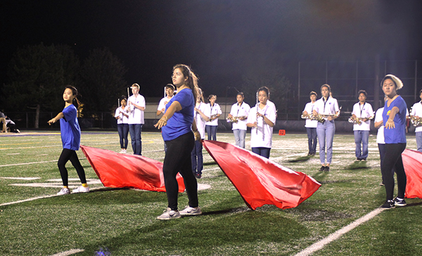 Vivacious Visuals: Performing alongside her teammates, junior Taylor Woitesek (center) partakes in Color Guard’s first performance of the year at South’s first home football game on Aug 30. The season has since ended, but Color Guard, along with the marching band, won Grand Champions at their final competition in Sandwich, Illinois. 