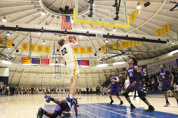 Jumping to the hoop, senior Gavin Morse goes up for a shot against the Niles North Vikings. The Titans beat the Vikings 70-59 on Dec. 7.