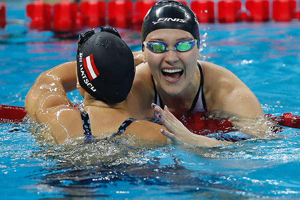 Olivia Smoliga (right) hugs Austrian swimmer, Caroline Pilhatsch, at the FINA World Swimming Championships after finishing the 50-meter backstroke on December 15, 2018. Smoliga placed first, beating Pilhatsch by 0.11 seconds. 