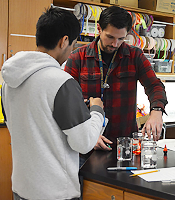 Helping Hands: Instructional Assistant Brendan Jacobi aids a student with his lab in a chemistry concepts class. 