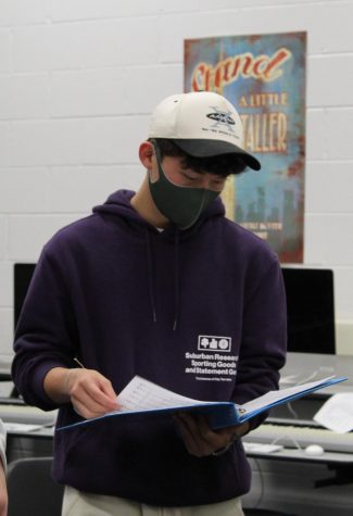 Cheerful Chung: Flipping through his binder of songs, senior Noah Chung practices with the a capella group Nine. A recent transfer to South, Chung is grateful to be involved in choir.