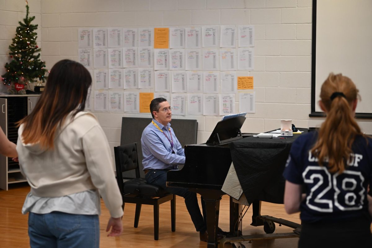 COOL KEYBOARD CLICKING: Sitting at the piano, Collaborative Accompanist Gregory Shifrin plays a warm-up for Glee Club as they sing along. Playing the simple accompaniment for the vocal warm-ups allows the choir to prepare their voices for more complex pieces later on in the rehearsal.