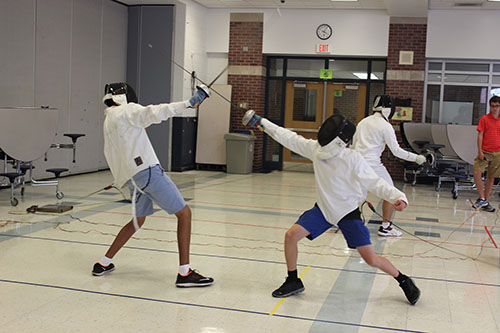 FIERCE FENCING: Fencing club members practice by competing in pairs. Club practices always use full body gear for protection.