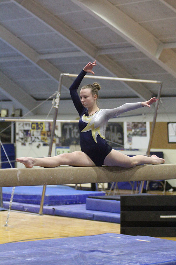BEAMING BALANCERS: Mid-cartwheel, sophomore Chloe Nourbash performs her beam routine at the Titan Quad (left). Focusing on keeping her blalance, sophomore Ellie Barberies holds the splits during her beam routine. The girls have a current record of 4-1 and look to perform well in conference. 