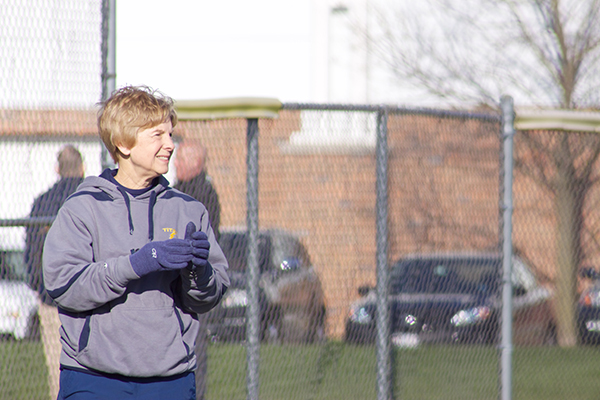 Standing on the third base line, Kay Sopocy, varsity softball coach, smiles while clapping her hands during a game against Evanston on April 12. Sopocy is finishing off her 24th year of coaching for the GBS softball team.