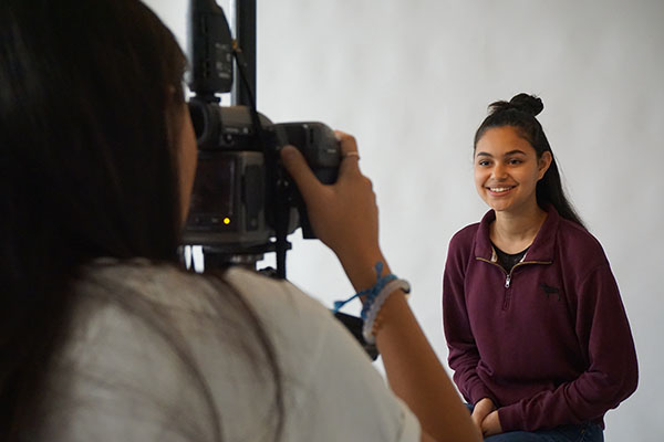 SMILING SUQI: Posing in one of the newly constructed photography rooms, sophomore Jena Suqi grins for sophomore Yoon Kim. Expanded space for the elective is one of a number of changes made as a result of the merge.