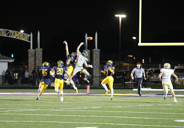 Friday night lights: Attempting to intercept the ball, junior Andy Sirakides (#8) jumps along side a St. Patricks runningback on Sept. 10. The Titans lost to St. Patricks by a score of 21-7.  