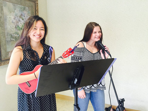 Smiling through   serendipity:  Strumming and singing, juniors Audrey Hwang and Zoë Gunderson respectively rehearse for their upcoming shows. The two met in 2016 through the Glenview Rock House and soon established themselves as a band entitled Serendipity.