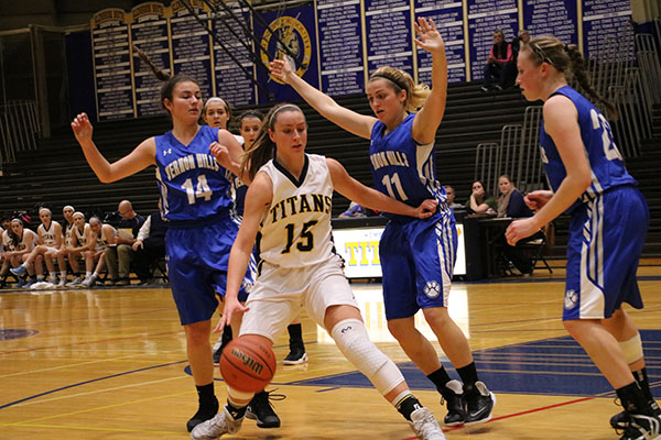 Blocking two Vernon Hills defenders, senior captain Carie Weinman (left) dribbles the ball and gets ready to shoot a layup. Extending her arms past the defenders, Weinman (right) launches herself to complete the layup; the Titans beat Vernon Hills on Nov. 29 by a score of 46-40.