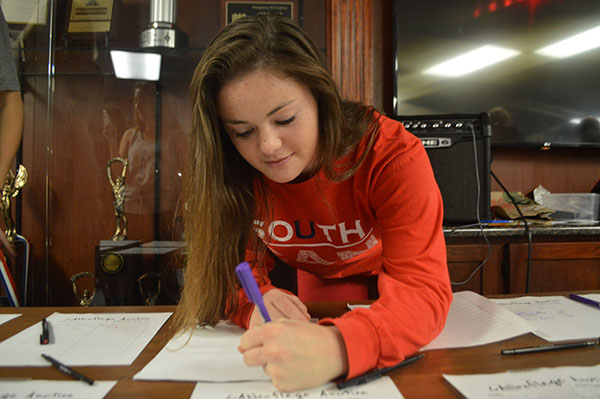 CAN-DO ATTITUDE: Preparing bidding sheets for the Canned Food Drive Silent Auction on Nov. 18, Carolyn Kuhn, senior class treasurer, assigns a value to an item. The Silent Auction was one of the various events organized by Student Council in order to reach the goal of 100,016 cans. 