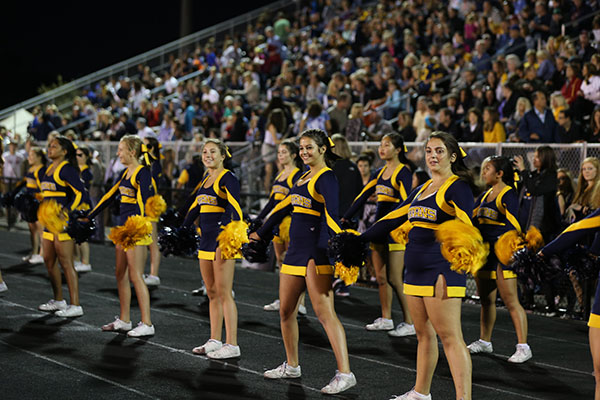 cheering   the   champs: Smiling at the field, junior Hallie Saperstein (left), sophomore Caroline Schrenzel (middle), and junior MariaElena Kouriabalis (right) cheer on the varsity football team. The Cheerleaders were at every Friday night game this season.