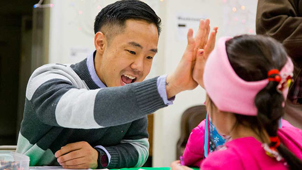 KEY CLUBIN’ KOO: High-fiving a student from Passages Charter school, Josh Koo, incoming assistant principal of student services, praises a young participant at an Eat ‘N’ Read event. According to his coworkers and students, Koo’s energy and compassion make him qualified to assume his new position starting with the 2017-2018 school year.