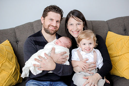 Dozing Daughter:  Cradling his daughter, Science Teacher Brandon Tucker smiles alongside his family members. In Nov. of 2016, Tucker took six days leave from teaching to help his wife welcome and care for their newborn baby. Photo courtesy Brandon Tucker