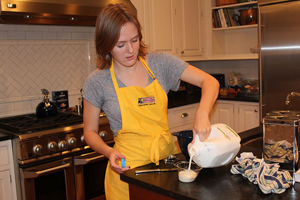 Cautiously measuring the amount of milk needed for her recipe, junior Kate Voss  works to create a delicious meal. Voss is the president of Souths new club Cooking for a Cause, which combines cooking with community service. Photo courtesy by Kate Voss