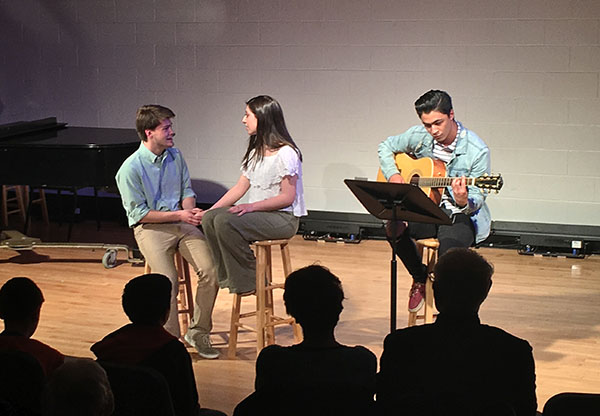 Singing for Service:  Performing with Yael Sheinfeld and Kai Erber, Jack Riley (seated on the left), senior academy student, sings a song with a message of love and acceptance. Riley held a concert on May 21 with the goal of raising money and collecting clothing for the WINGS program, which aims to provide services to domestic abuse victims. Other academy seniors participated in service projects that aligned with a global or local issue they chose to research.