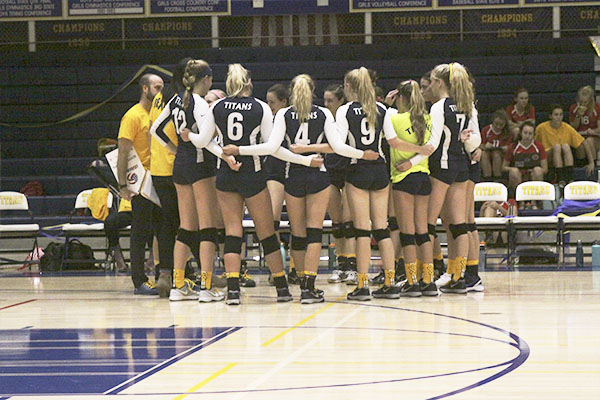 GOING FOR THE GOLD:  Huddling during their “Go Gold” match against Maine South, the women look to Head Coach Kelly Dorn for guidance. The Titans lost to the Hawks on Sept. 26, 35--37.