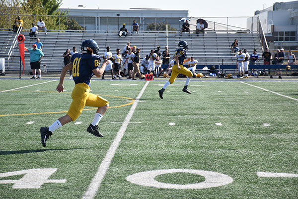 TACKLING GENDER NORMS: Freshman Katie Pribyl sprints down the field on a kickoff against the St. Patrick’s Shamrocks (left). Pribyl lines up, readying against the snap count prior to a play against the Shamrocks (right). Priybl is the first female football player in the GBS program, according to football coach Matt Hoshaw. 