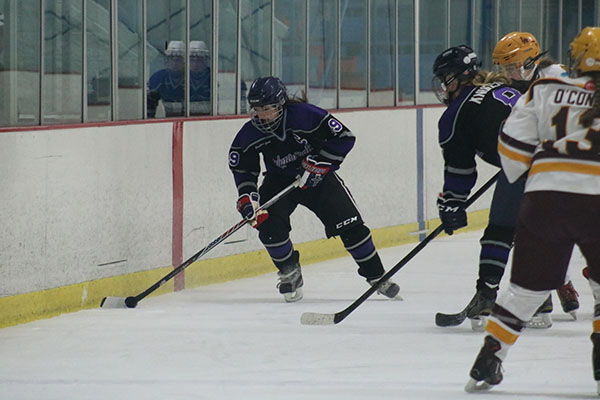 HOCKEY HEROES:   Facing up against an opponent, Glenbrook captain Chloe Carroll (left) readies herself for a play against a Loyola Rambler on Dec. 17. Gaining possesion of the puck, defenseman Addison Carr looks to advance up the ice against Loyola. Glenbrook tied with the Ramblers by a score of 2-2.