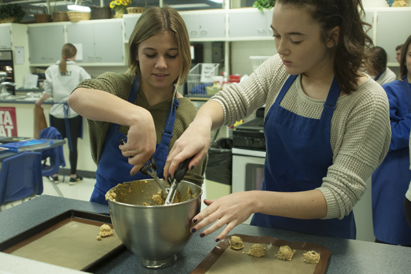 FANTASTIC FOODS:   Scooping cookie dough, freshman Dani Stadler (left) and Megan Butler (right) participate in foods one. They are preparing chocolate chip oatmeal cookies. Stadler plans on advancing to Foods two in the future because she loves learning about different foods and how to make them. 