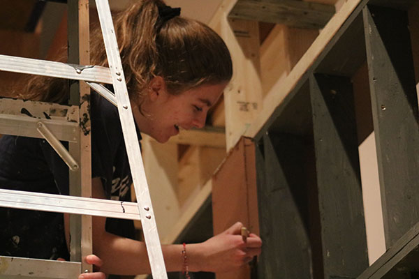 CREATIVE CONSTRUCTORS:   Balancing on top of a ladder, sophomore Hannah Dobos carefully paints the background set. All students are welcome to participate in set construction along with South’s Stage Crew. 