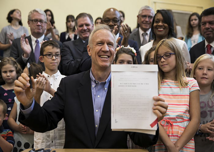 RAMBUNCTIOUS RAUNER: Holding a newly signed law, Governor Bruce Rauner smiles. Rauner passed a new budget for Illinois that included cutting P.E. requirements in public schools.