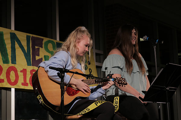 Strumming the guitar and singing into the microphone, sophomores Clare Dunne Murphy and Taylor Rudolph-Woitesek perform at Jamnesty on April 13. Several student bands at South perform at Jamnesty for peace and human rights.