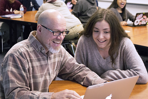 HICKS LENDS A HAND:   Opening up his laptop, Daniel Hicks, social studies teacher, pulls up a presentation for junior Eva Papajohn about the singers Little Richard and Chuck Berry as a supplement for his lesson about 1950s pop culture. Hicks’s journey to become a teacher has been unorthodox, but he views his story as a source of hope for others.