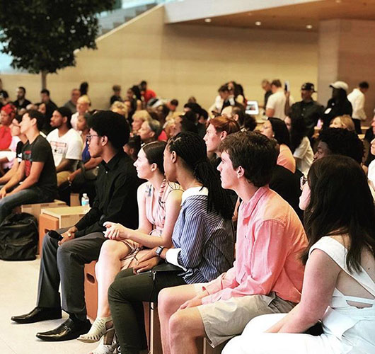 What   a   view:  Sitting amongst his fellow summer interns, senior Brendan Garvey (in the salmon shirt) attends a viewing party at an Apple store in downtown Chicago. Through this internship at Apple, Garvey hopes to explore his options for a possible future career. 