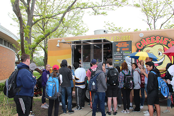 Waiting in line during the lunch blocks on May 17, students patiently stand outside in the rain to get a grilled cheese from Cheesie's food truck stationed in the autos courtyard. South’s annual Spring Fling is intended to boost student morale and celebrate the rapidly approaching end of the year.