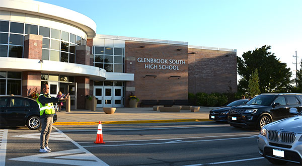 Parking lot patrol: Directing traffic, one of the three parapros stationed outside the main entrance stops cars to allow students to cross the street. In 
 previous years, there were only two parapros outside, but another was added at the beginning of this year.